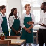 Jefes de restaurante hablando con los camareros con delantales verdes